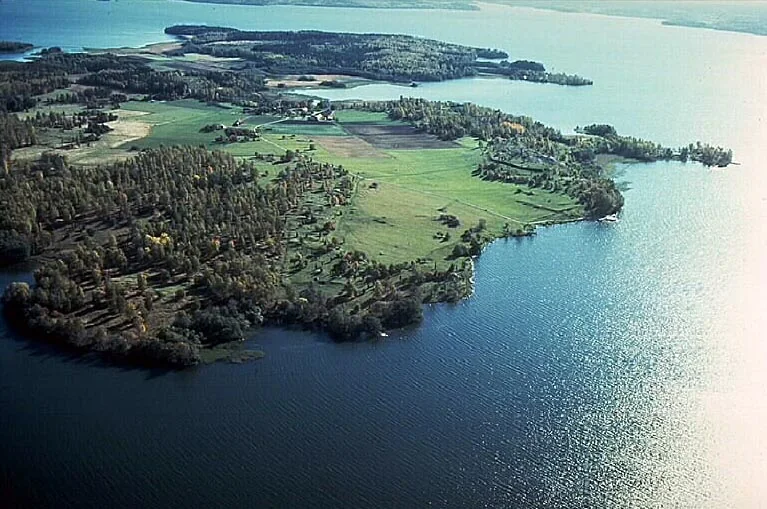 Flygbild över Birkauddens öppna marker, skogsdungar och omgivande vatten i Mälaren.